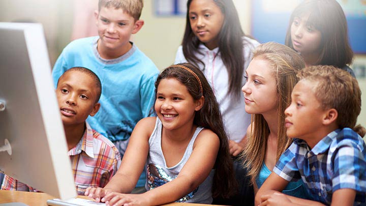 Smiling 3rd grade students start a video conference in the classroom