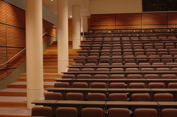 An empty lecture hall with tables and chair stadium seating